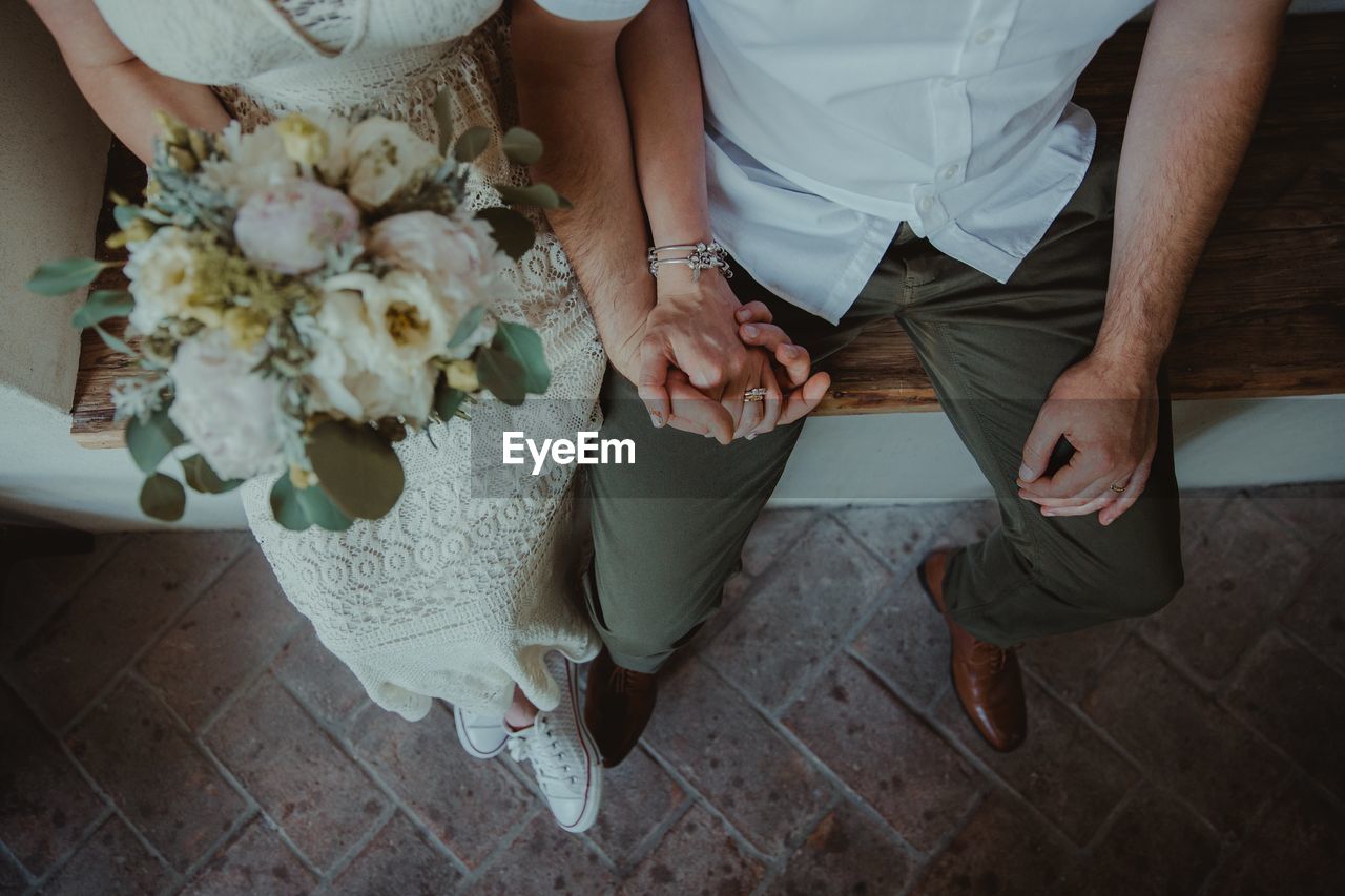 Low section of couple holding hands during wedding ceremony