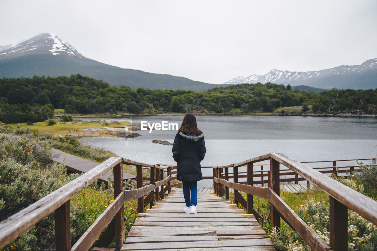 Rear view of woman looking at lake against mountain