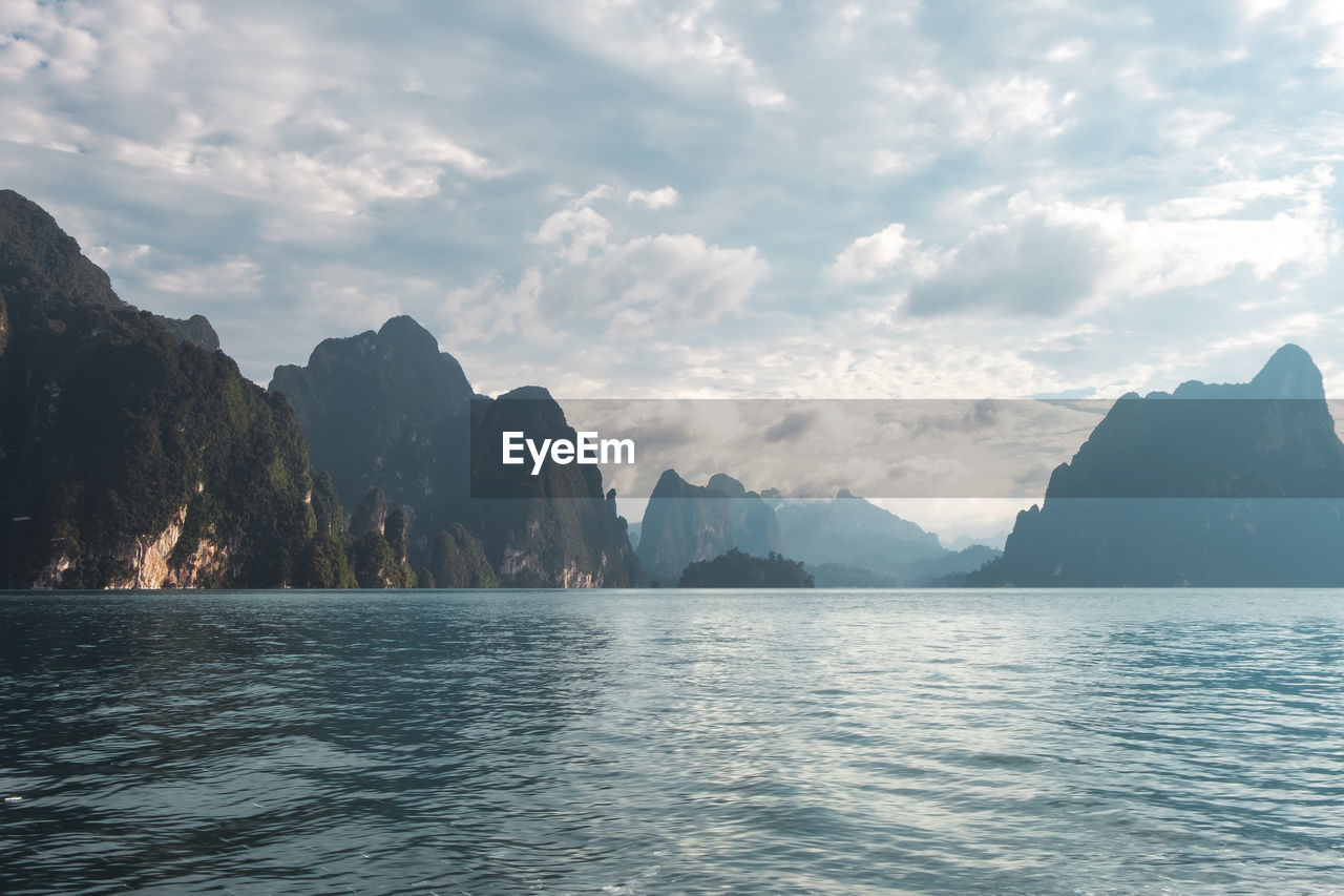 Panoramic view of sea by mountains against sky