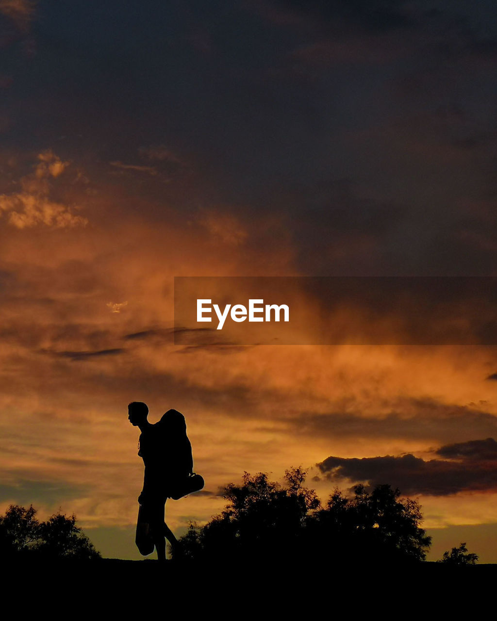 Silhouette man standing against orange sky