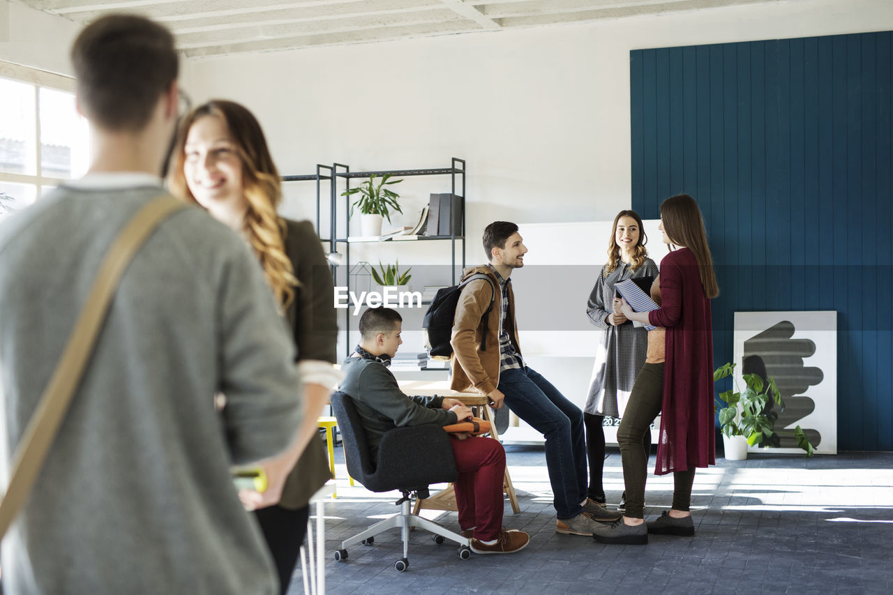 Friends talking while standing at table in classroom