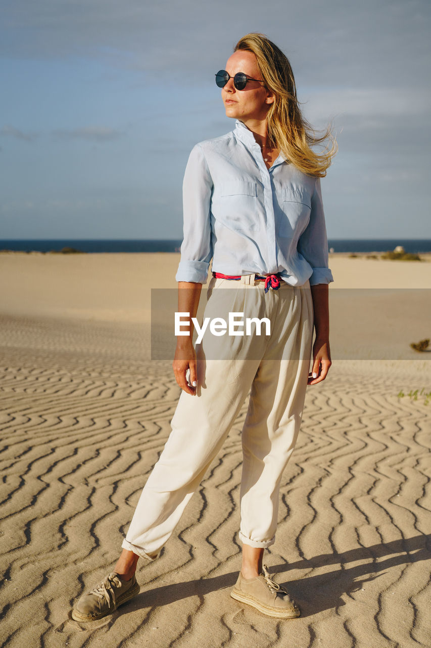 Full length of woman standing on sand in desert against sky