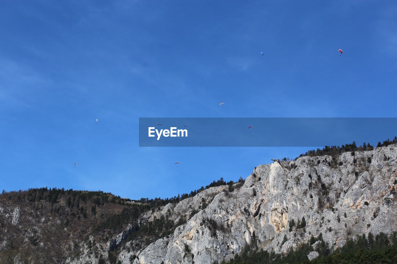LOW ANGLE VIEW OF BIRDS FLYING OVER MOUNTAINS