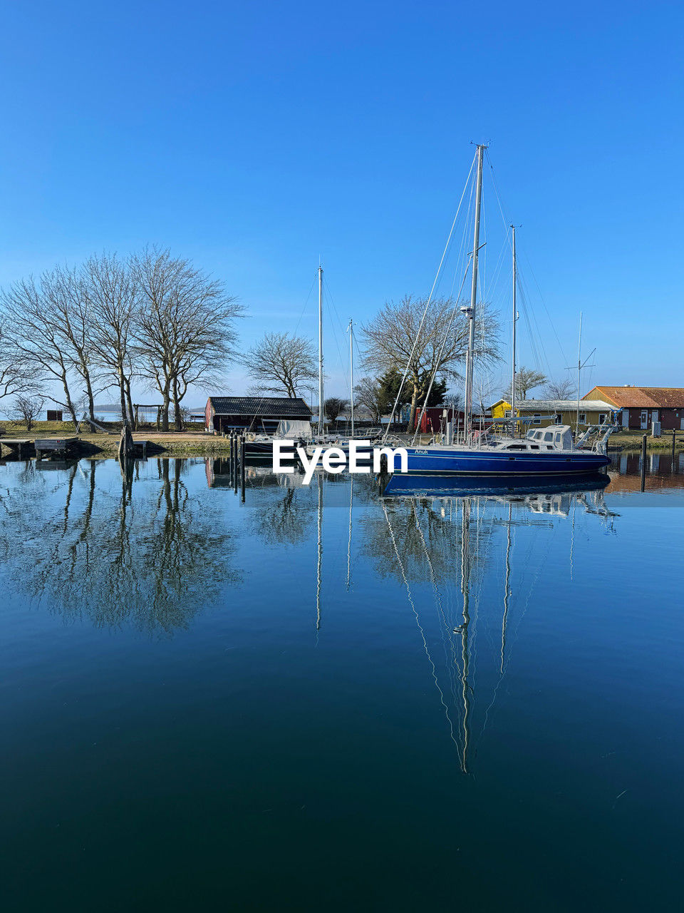water, reflection, dock, nautical vessel, marina, sky, transportation, mode of transportation, nature, blue, sea, no people, clear sky, vehicle, ship, boat, sailboat, moored, harbor, tranquility, day, architecture, outdoors, bay, beauty in nature, tree, tranquil scene, travel destinations, pole, travel, waterfront, scenics - nature, mast, watercraft