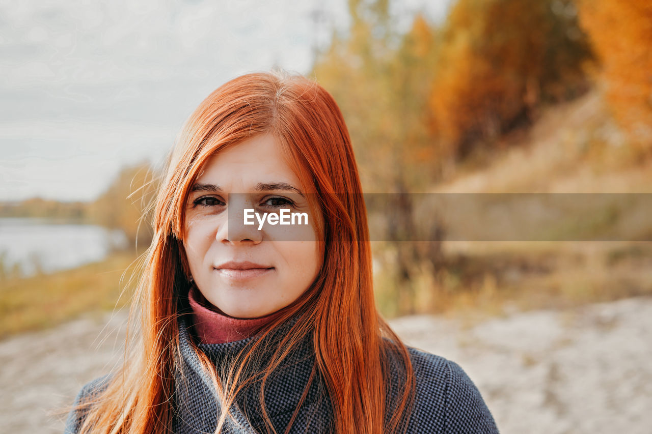 Portrait of happy young red haired woman smiling and looking aside. local travel. 