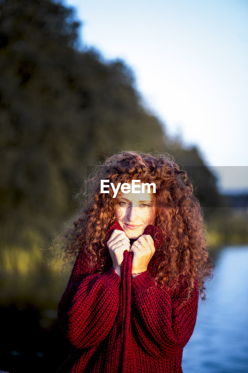 CLOSE-UP PORTRAIT OF YOUNG WOMAN WITH RED HAIR AGAINST SKY