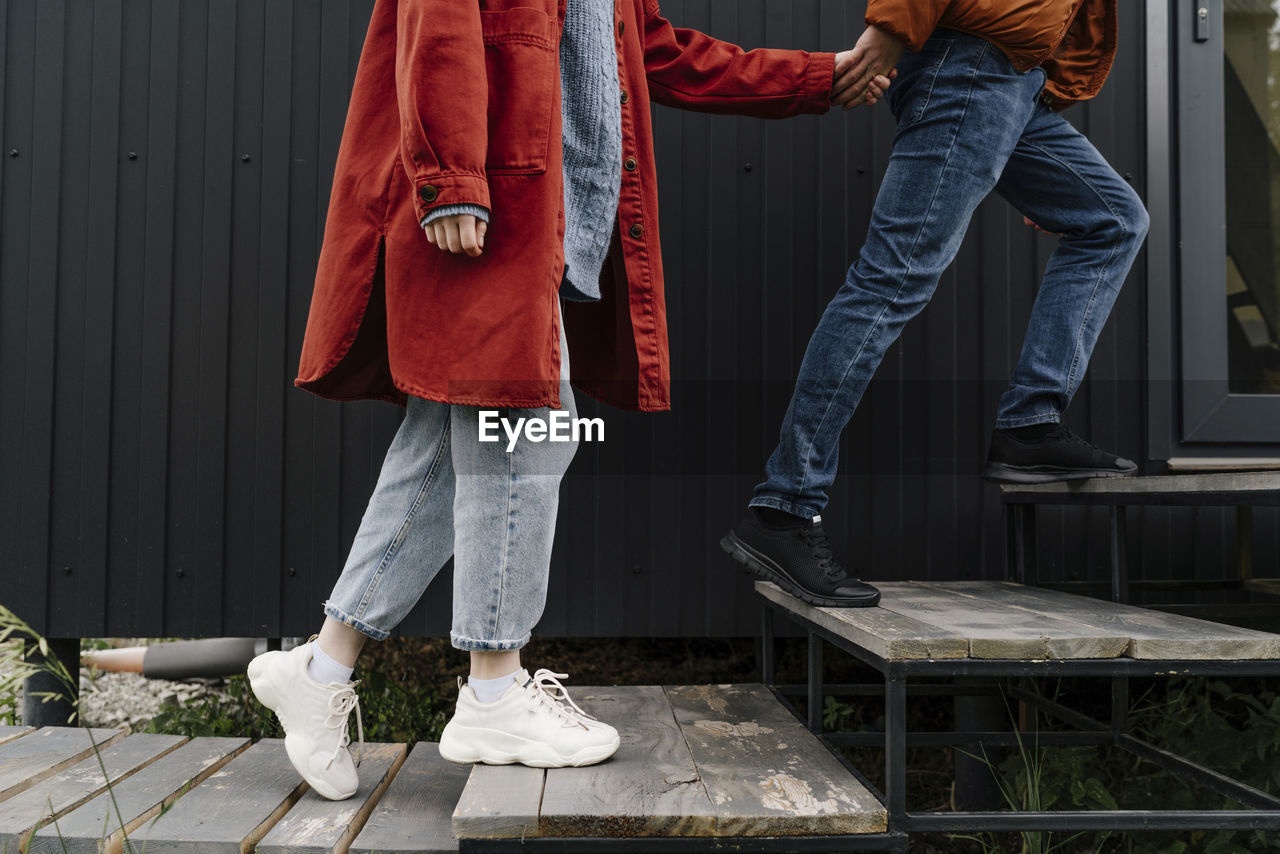 Couple holding hands stepping into house