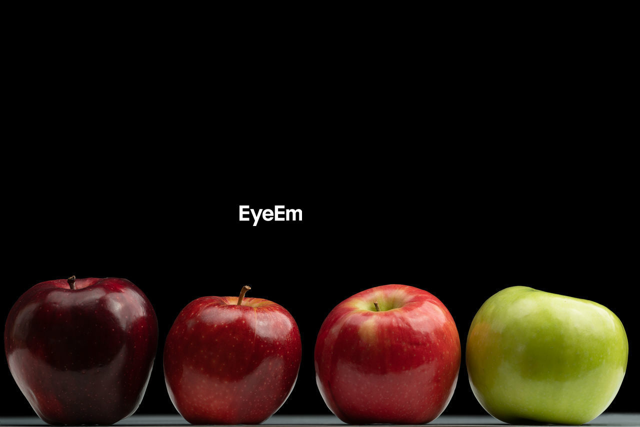 4 apples in a row on black background