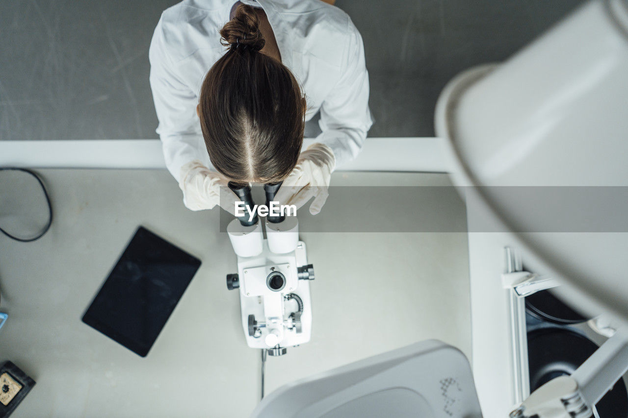 Young scientist working with microscope in laboratory