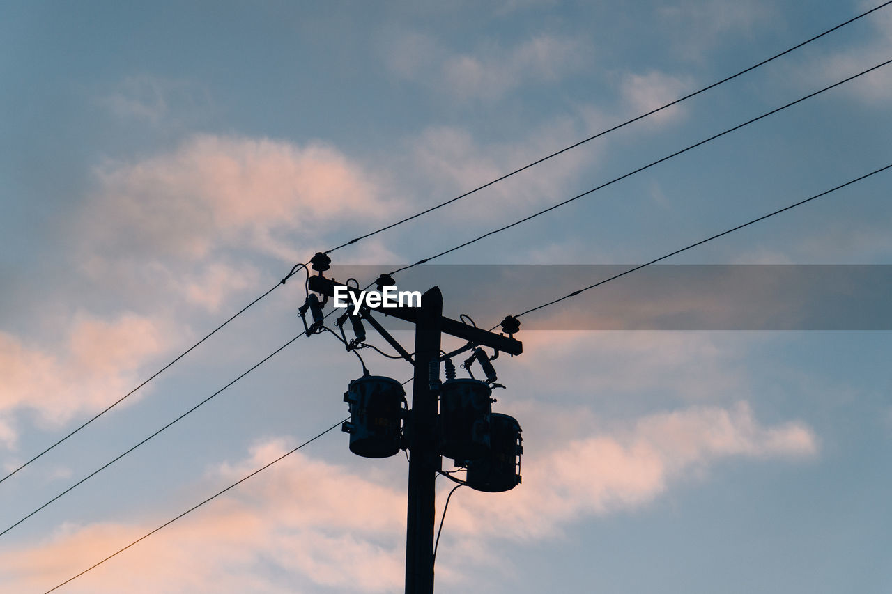 Low angle view of silhouette powerlines and telephone pole  against sunset sky.