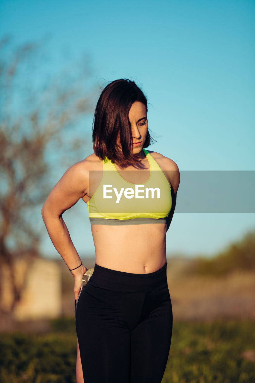 Beautiful woman standing on field against sky