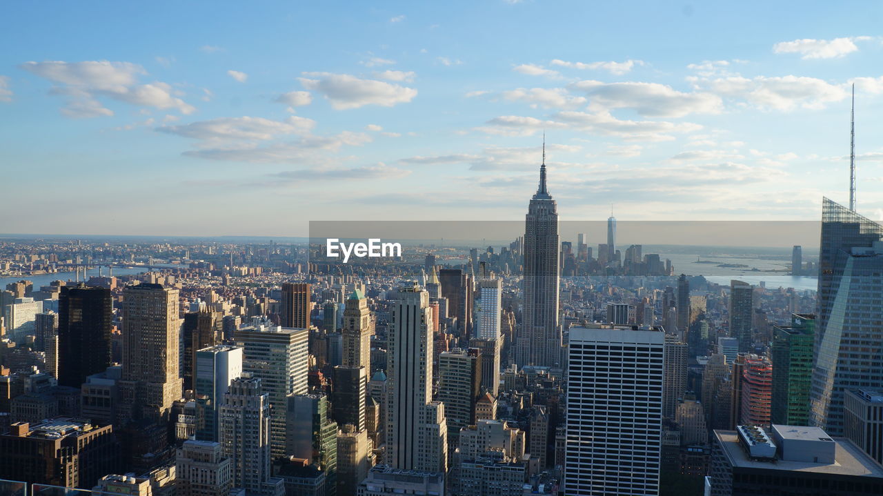 Aerial view of buildings in city against cloudy sky