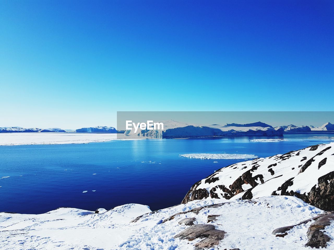 Scenic view of snowcapped mountains against clear blue sky