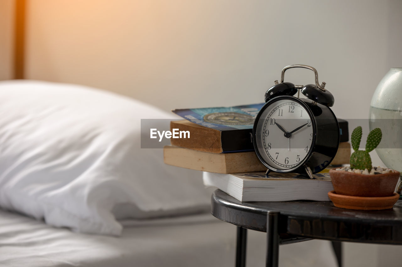 Close-up of alarm clock by bed on table at home