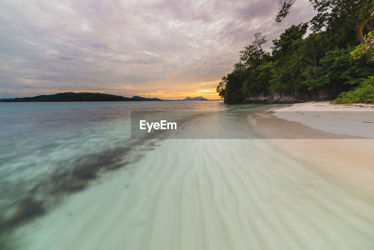 Scenic view of sea against cloudy sky during sunset