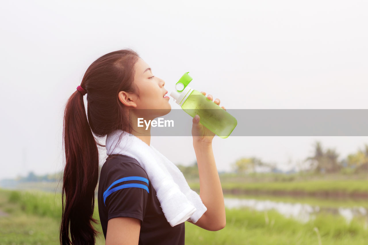 Side view of young woman drinking water