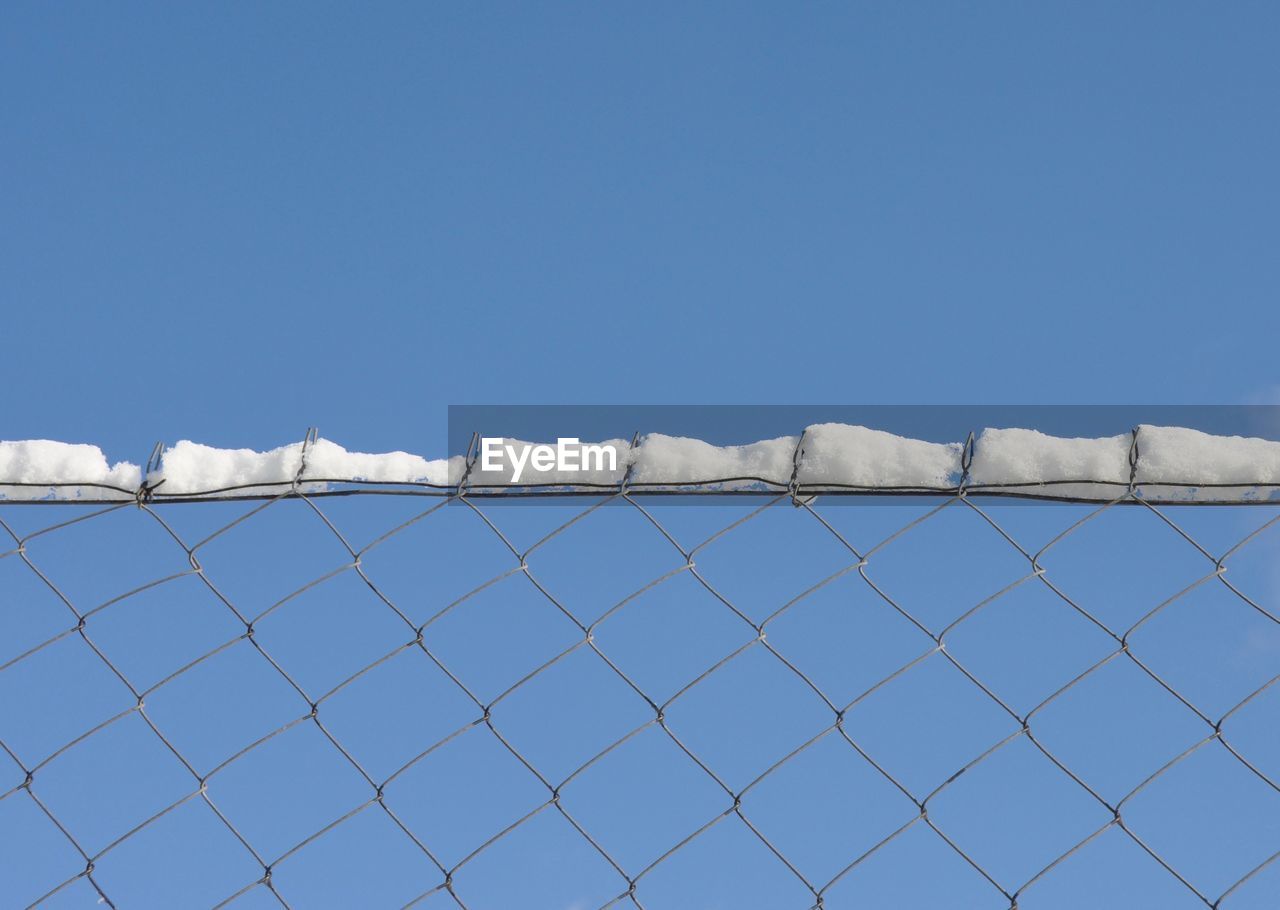 FENCE AGAINST CLEAR BLUE SKY DURING WINTER