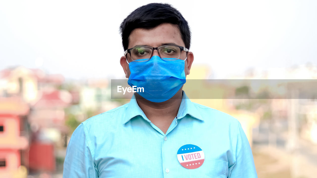 PORTRAIT OF MAN STANDING AGAINST BLURRED BACKGROUND