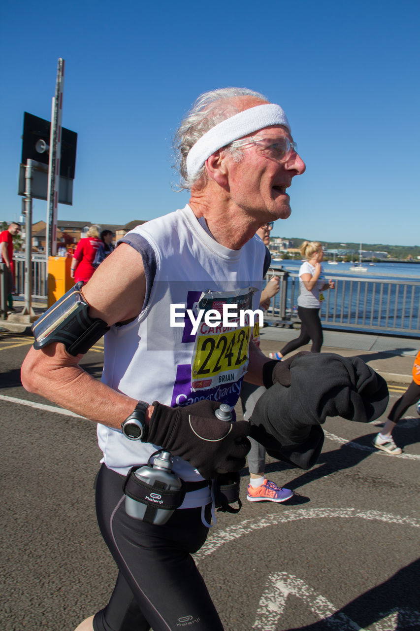 MAN HOLDING SUNGLASSES AGAINST CLEAR SKY