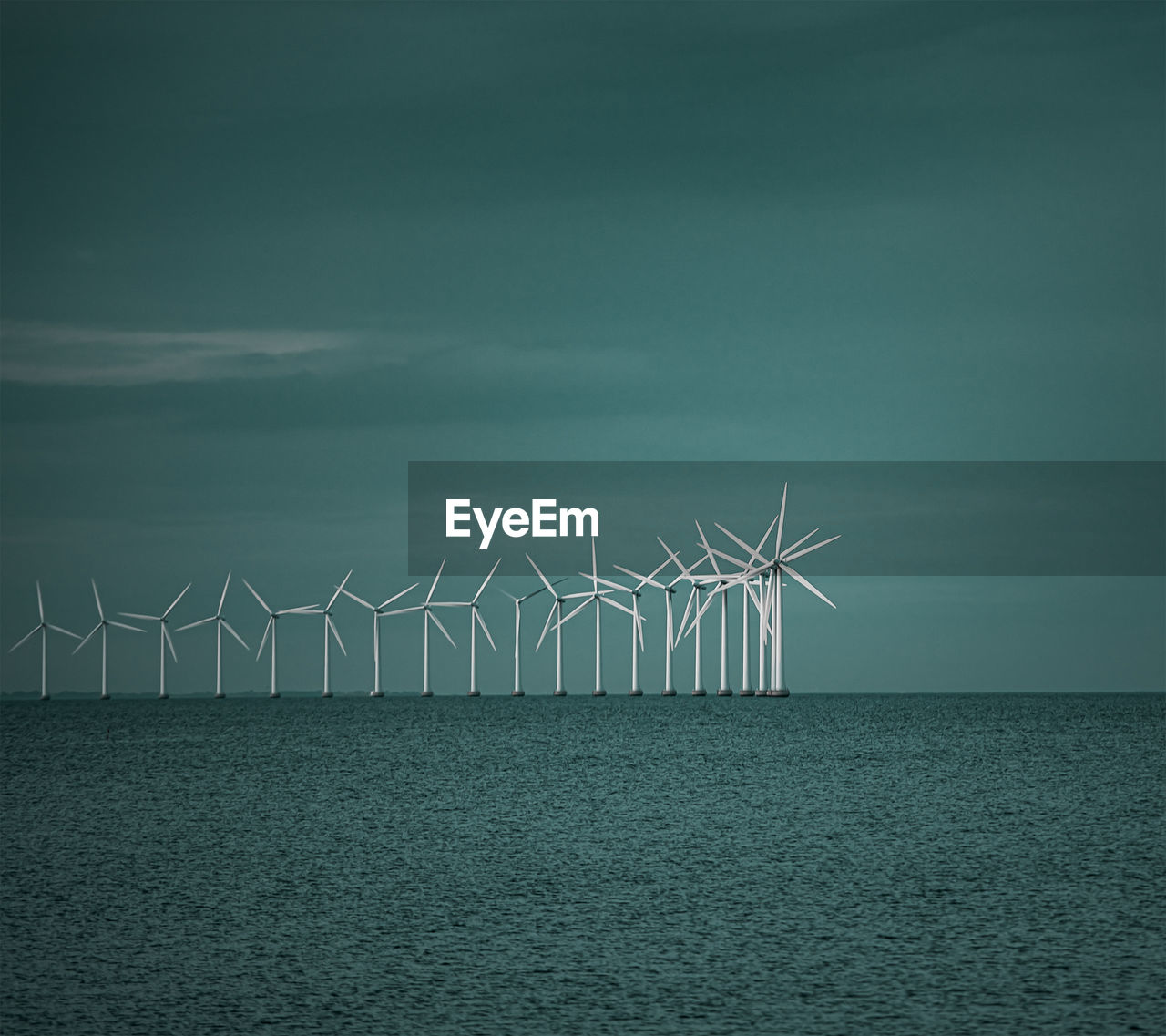 Wind turbines in sea against sky