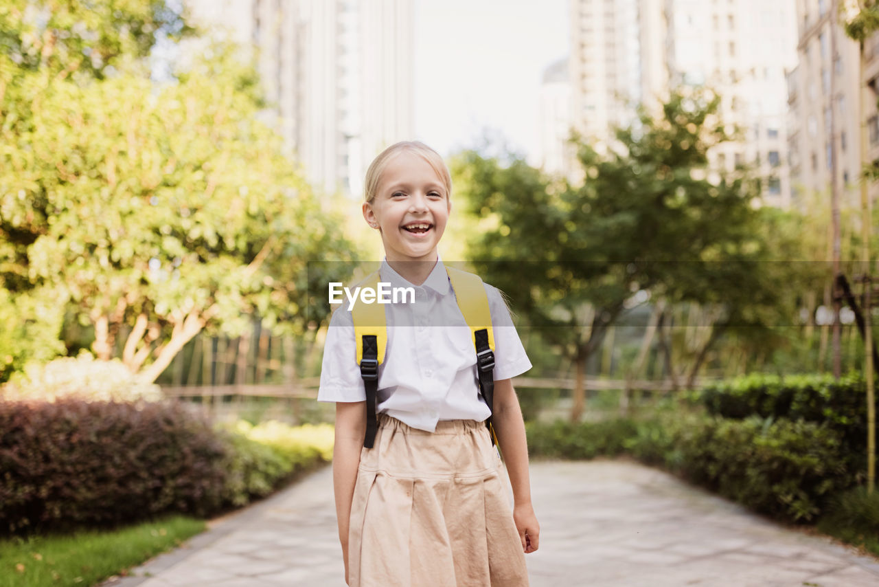 Back to school. little girl with yellow backpack from elementary school outdoor