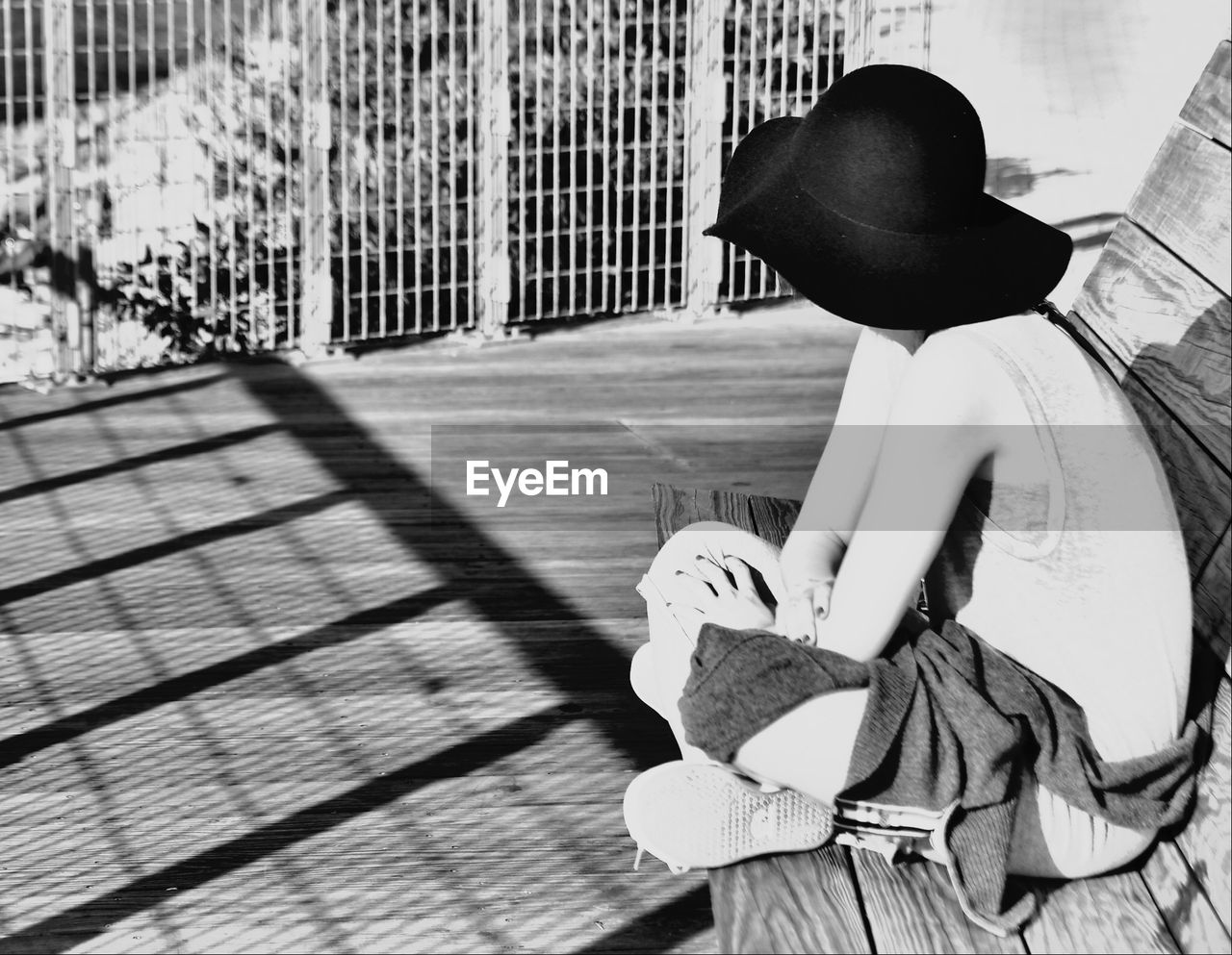 Woman wearing hat sitting on bench at park