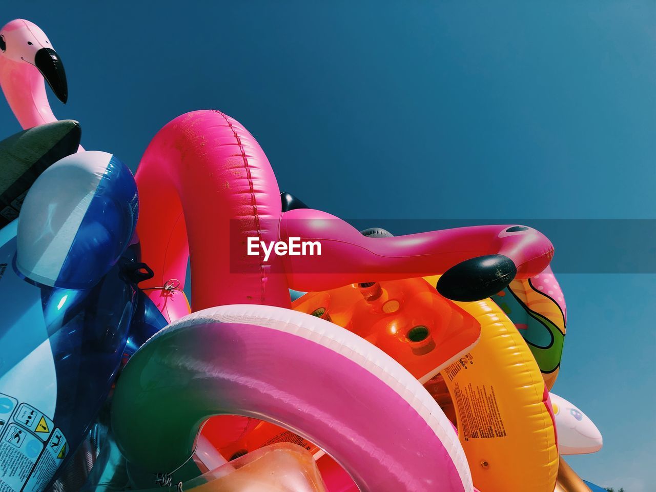 Close-up of various inflatables beach toys on beach against clear summer sky.