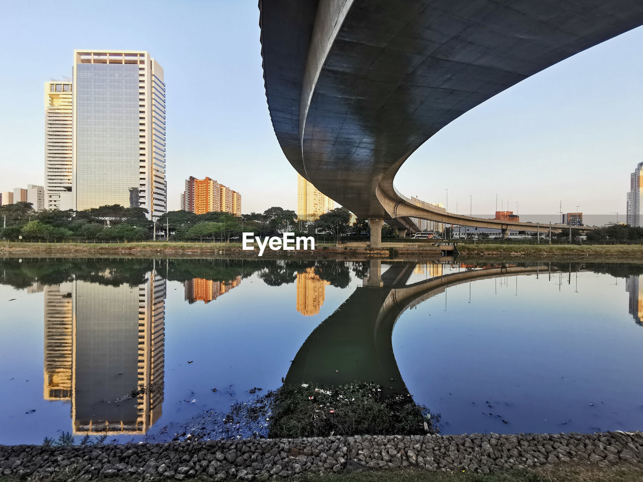 Arch bridge over river by buildings against sky