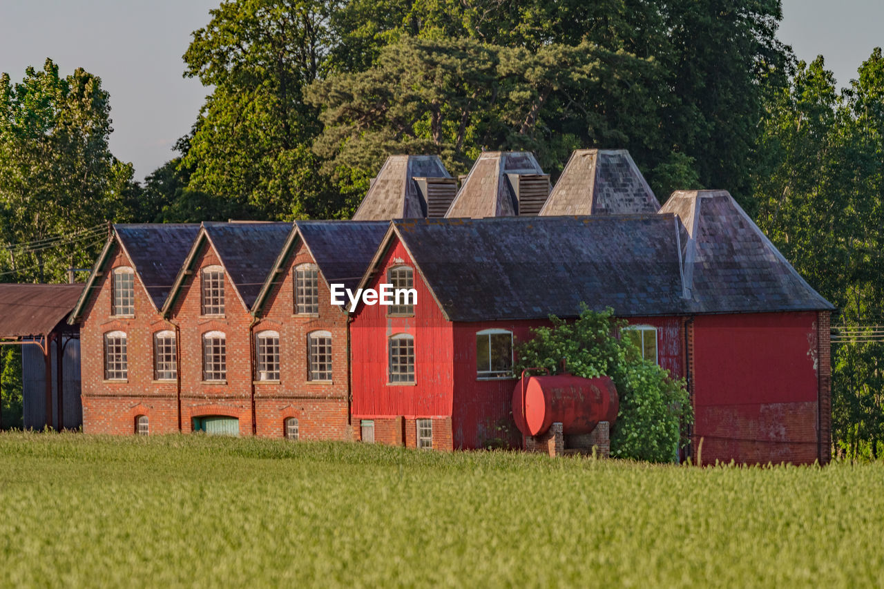 HOUSE ON FIELD AGAINST TREES AND BUILDINGS