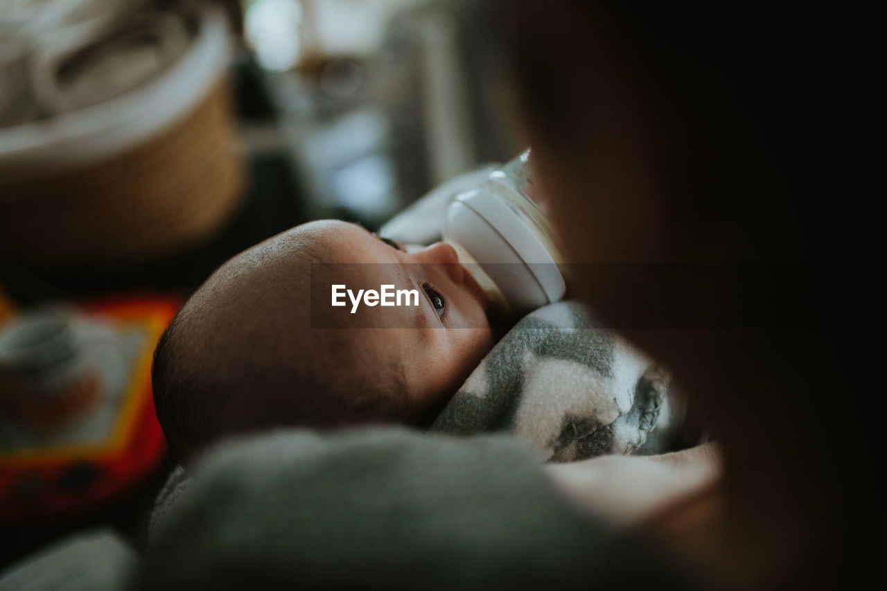 Close-up of mother feeding baby boy while sitting at home