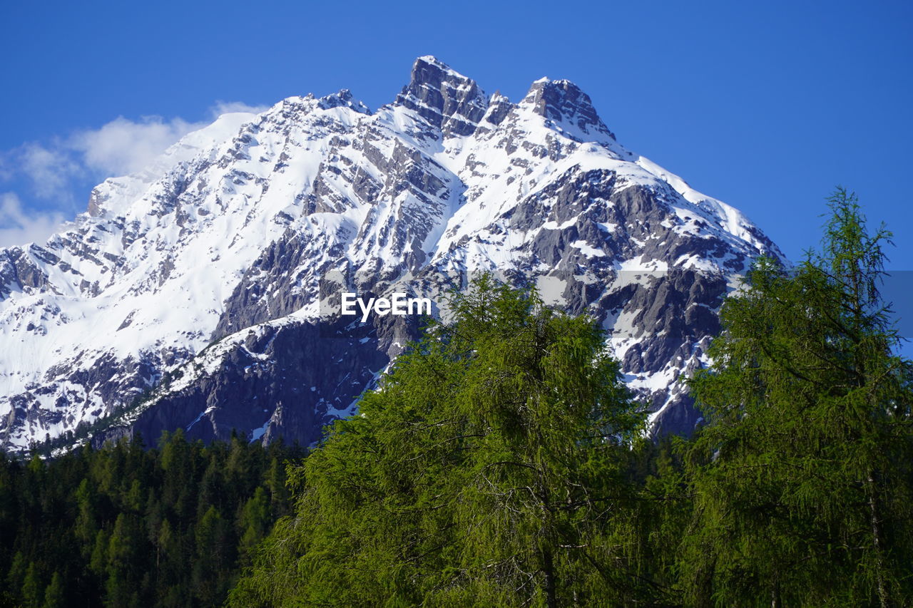 Low angle view of snowcapped mountains against blue sky