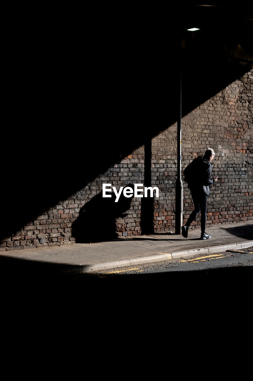 SHADOW OF MAN WALKING ON FOOTPATH IN CITY