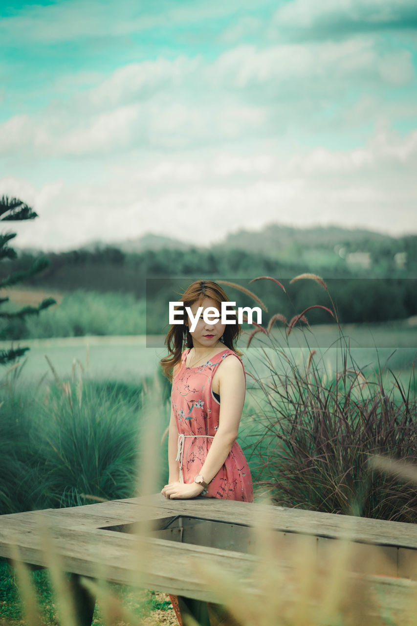 Beautiful young woman standing against sky