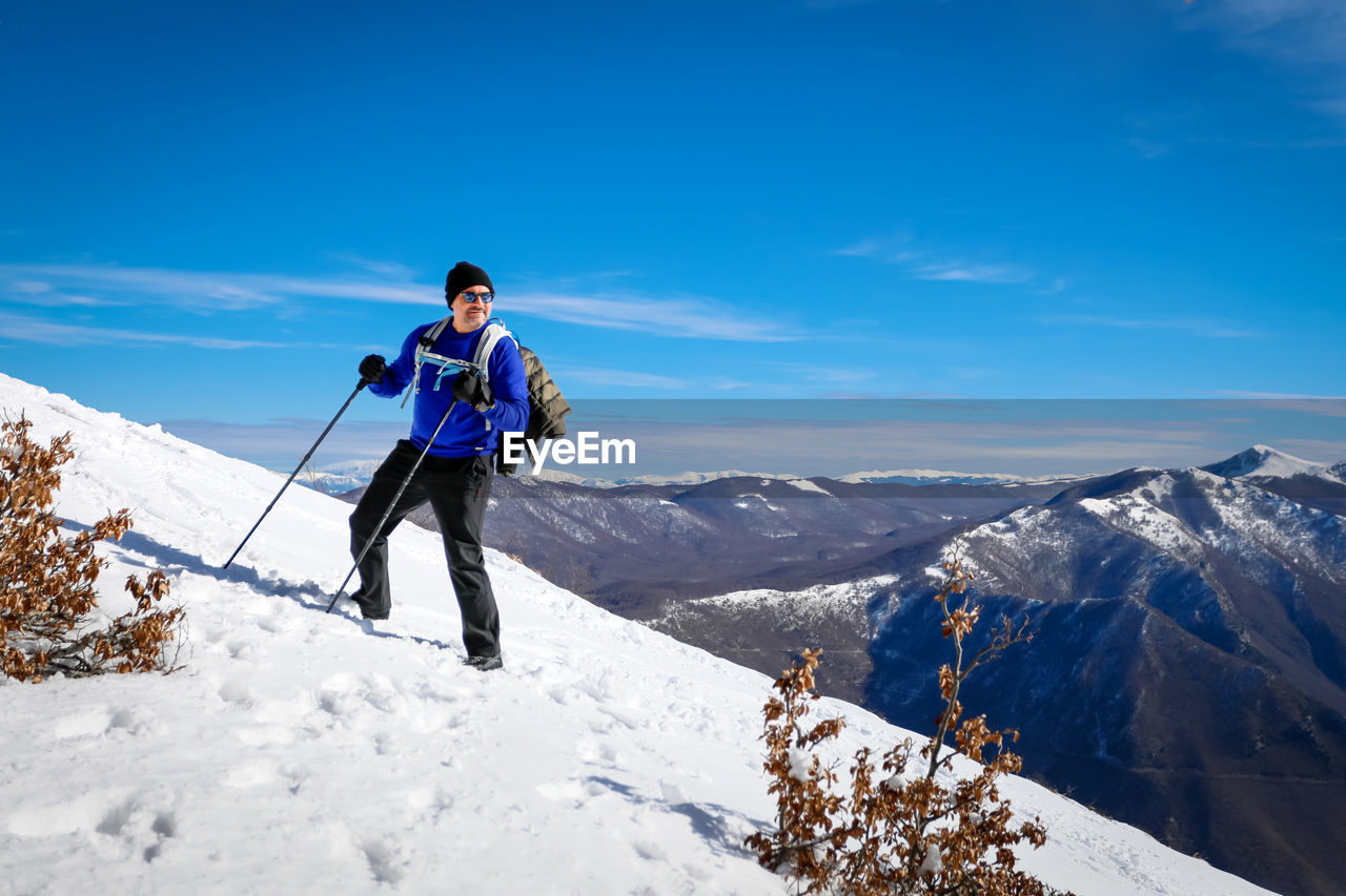 View of man standing on snowcapped mountain against sky