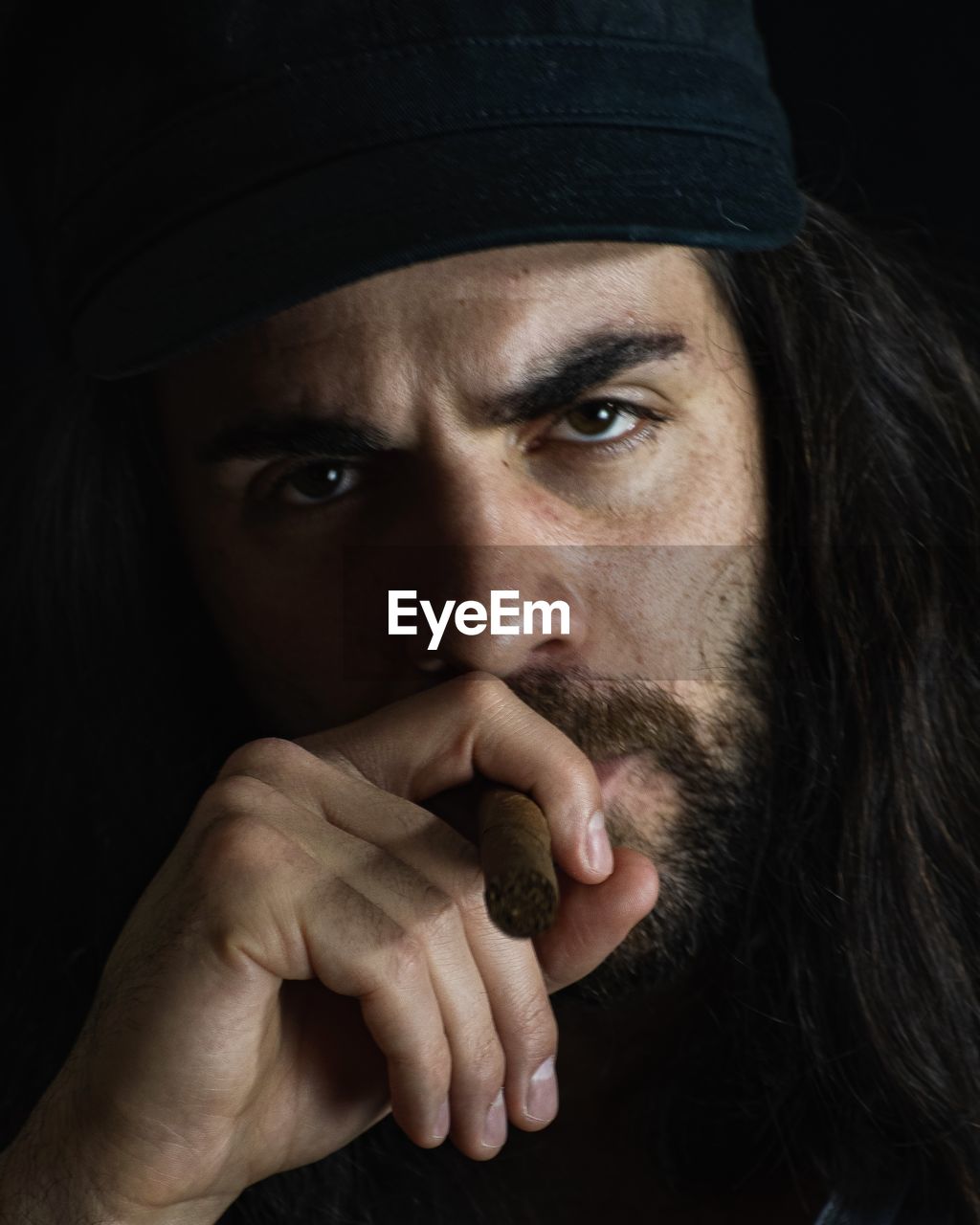 Portrait of man holding cigar against black background