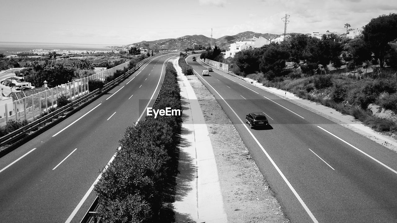 VEHICLES ON ROAD AGAINST SKY