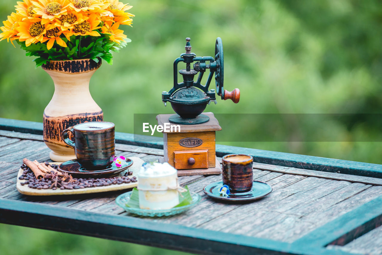 flower, flowering plant, plant, nature, table, freshness, no people, food and drink, vase, wood, food, yellow, beauty in nature, outdoors, day, focus on foreground, container, summer, cup