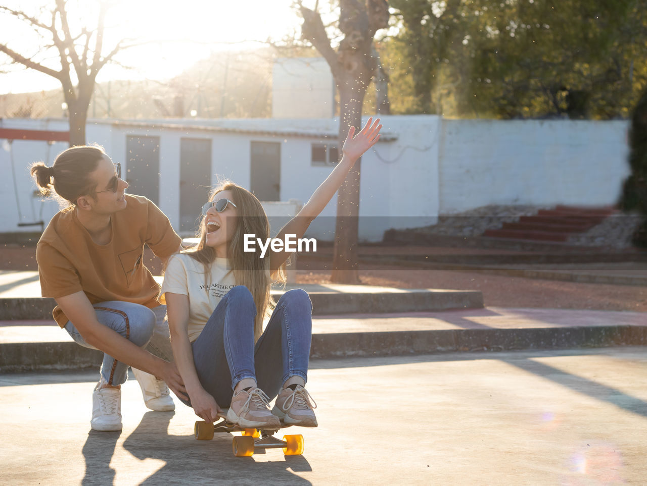 Heterosexual young couple having a good time while using a longboard in the afternoon light