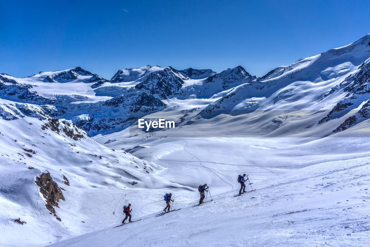 People walking on snowcapped mountain against sky