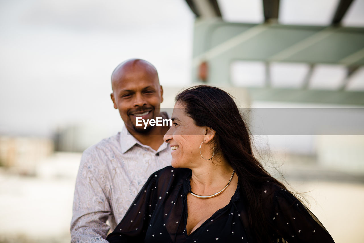 Multiracial late forties couple embracing at sunset in san diego