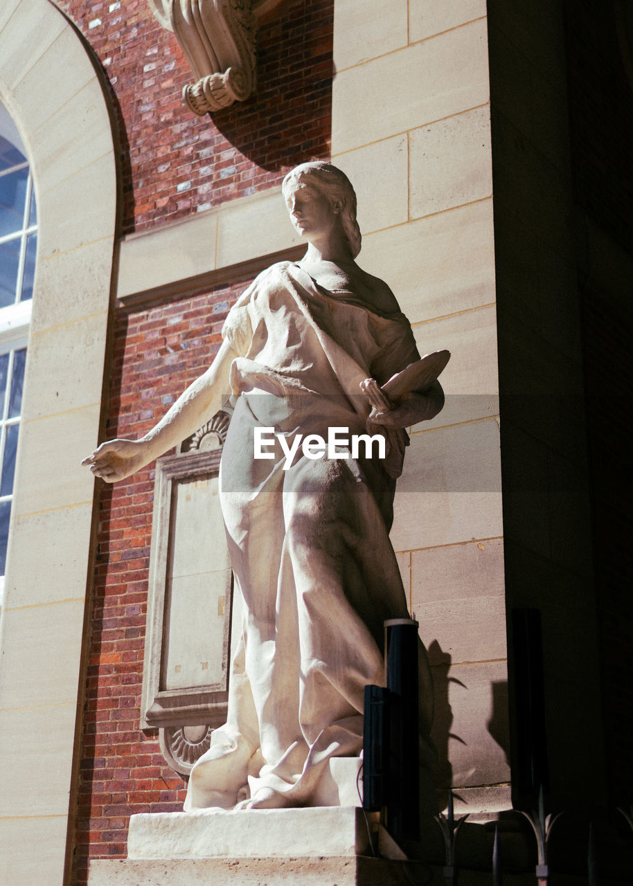 LOW ANGLE VIEW OF STATUE AGAINST WALL