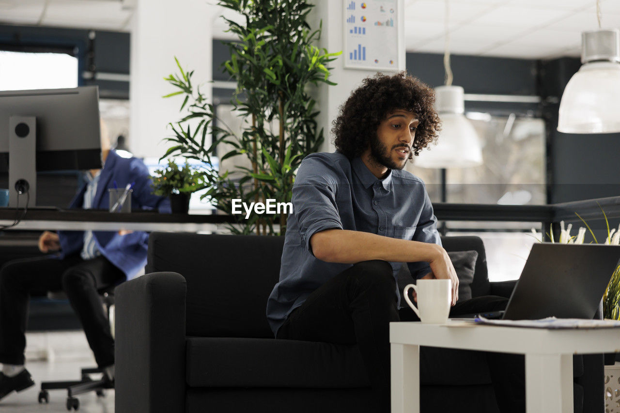 side view of young woman using laptop at office