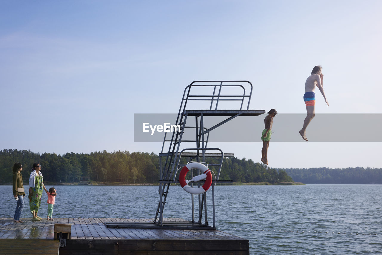 Teenage boys jumping into water from jumping tower