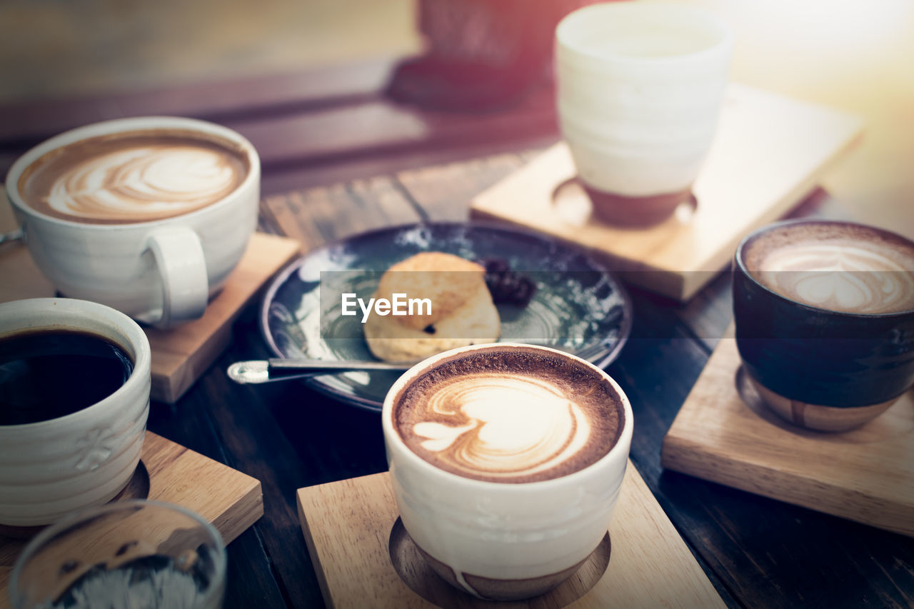 Breakfast with coffee and bread on wooden table under sunlight, vintage color tone, meeting concept.