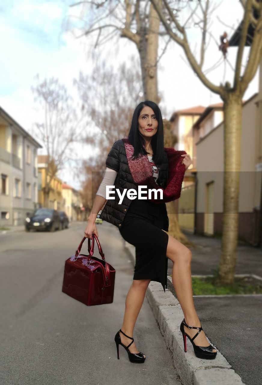 Full length portrait of woman standing on footpath