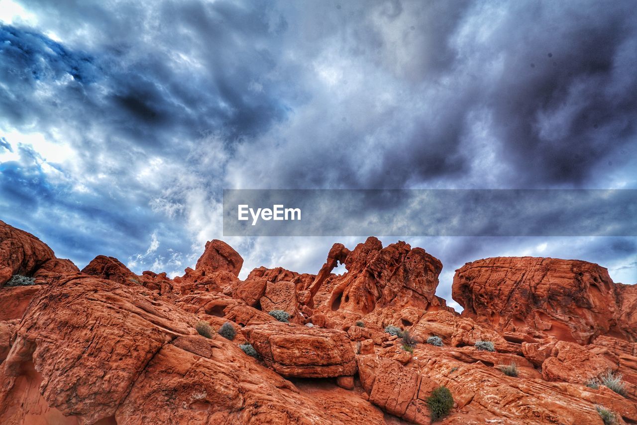 Low angle view of rock formations against cloudy sky