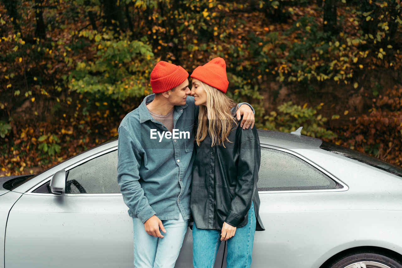 A young couple in love is embracing near the car.