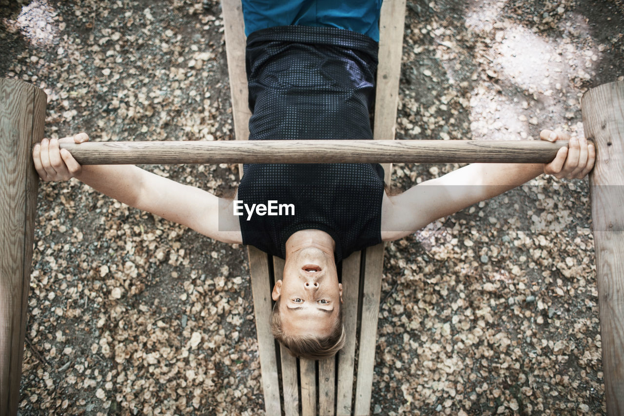 High angle view of man lifting wooden weight at outdoor gym
