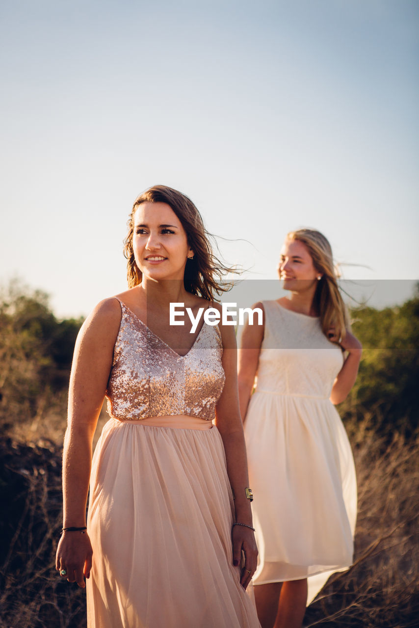 Young women standing against sky