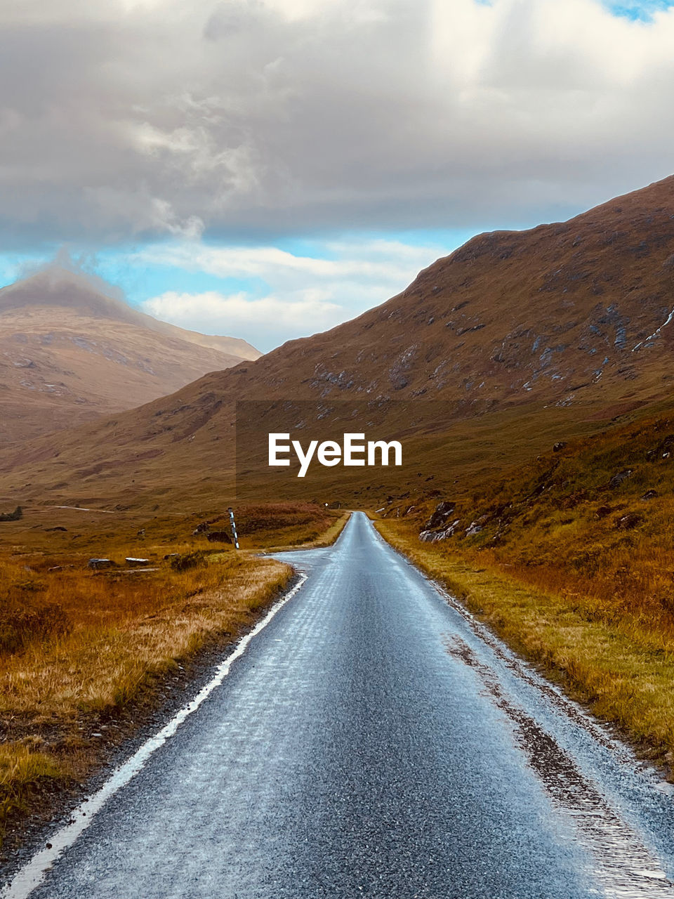 Empty road amidst mountains against sky